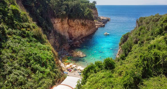 People swimming in crystal clear blue waters on a hidden beach. Bird View of a beautiful golf called Regina Giovanna in Sorrento, Italy