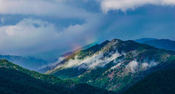 Photo of Mount Olympus, Cyprus, amazing cloudy mountain peak with a rainbow.