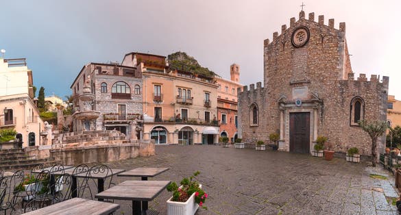 Cathedral of Taormina and fountain on the square Piazza Duomo in Taormina at rainy sunrise, Sicily, Italy