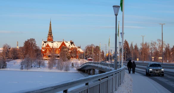 photo of sun and snow on Umeå City Church from 1894 in Umeå in north of Sweden, with the bridge across the frozen river in the front.