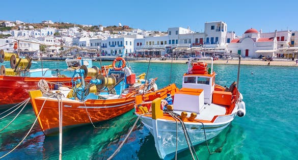 Photo of harbour with wooden fishing boats in Chora town on sunny summer day, Mykonos island, Greece.