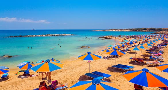 Photo of Coral Bay Beach with sunbeds and umbrellas in Paphos, Cyprus.