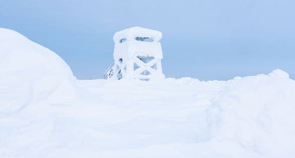 Photo of Iso Pyhätunturi lookout tower covered with snow and frost on a winter day in Salla National Park, Northern Finland.
