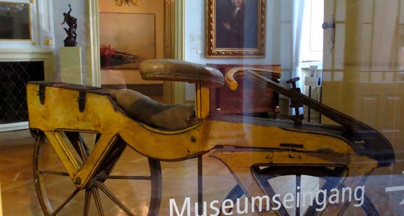  more details Passage to the inner courtyard of the Kurpfälzisches Museum with a view through safety glass into a salon on a trolley named after Karl von Drais, the developer