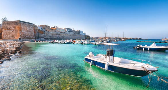 Several fishing boats at the Otranto harbour - coastal town in Puglia with turquoise sea. Italian vacation. Town Otranto, province of Lecce in the Salento peninsula, Puglia, Italy