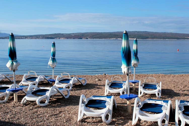 Photo of sunbeds and umbrellas on the beautiful beach of Dramalj, Crikvenica, Croatia.