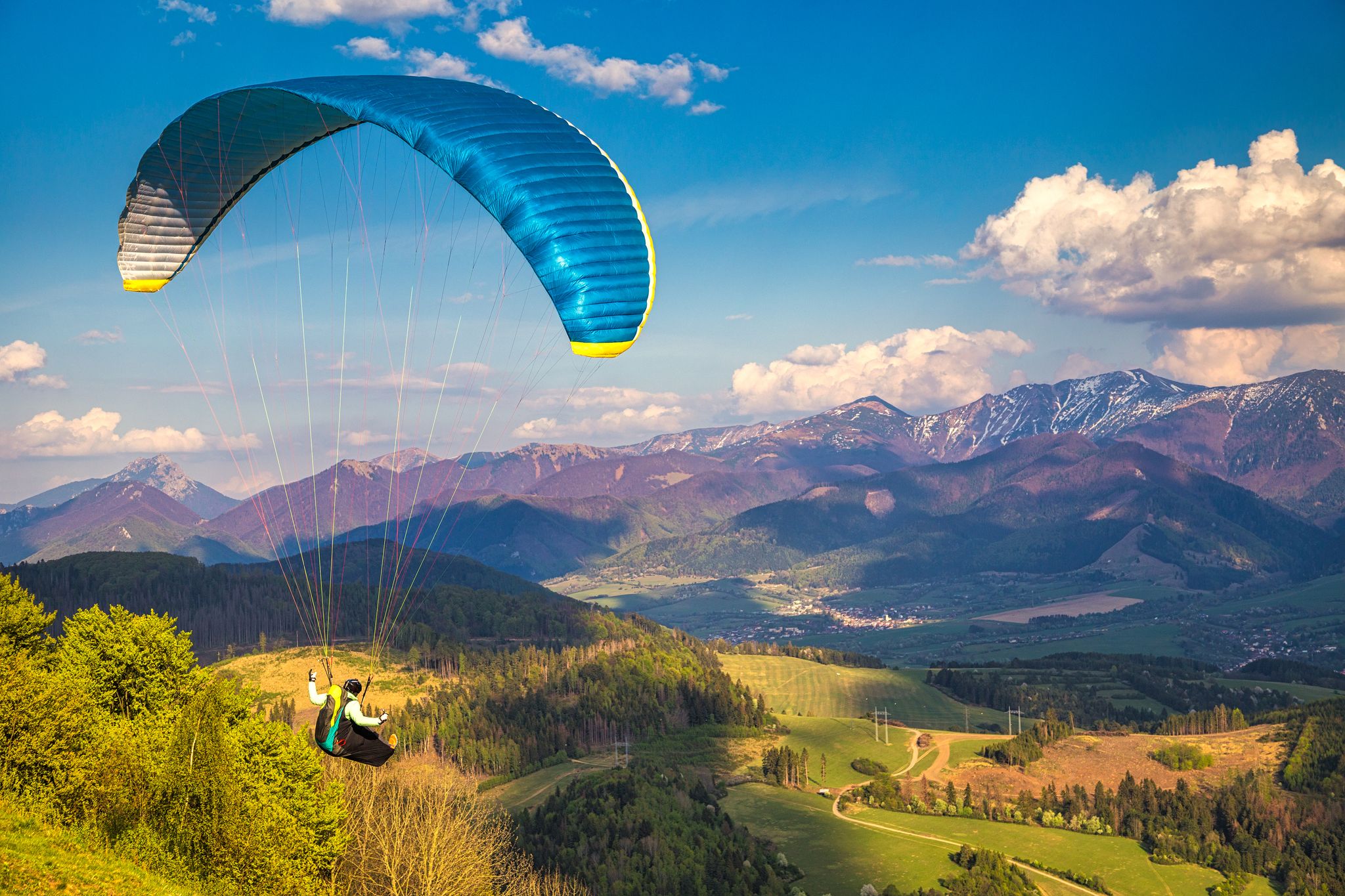 Flying paragliders from the Stranik hill over the mountainous landscape of the Zilina basin in the north of Slovakia. Mala Fatra National Park in the background, Slovakia, Europe.