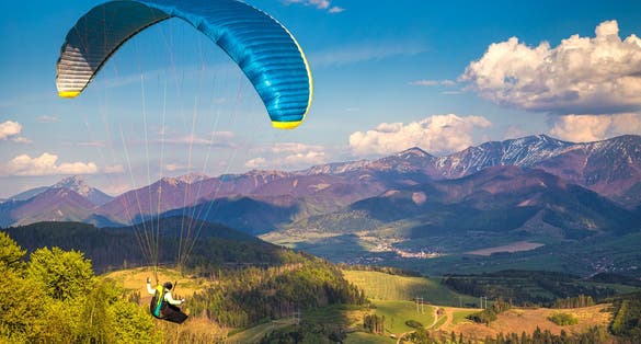 Flying paragliders from the Stranik hill over the mountainous landscape of the Zilina basin in the north of Slovakia. Mala Fatra National Park in the background, Slovakia, Europe.