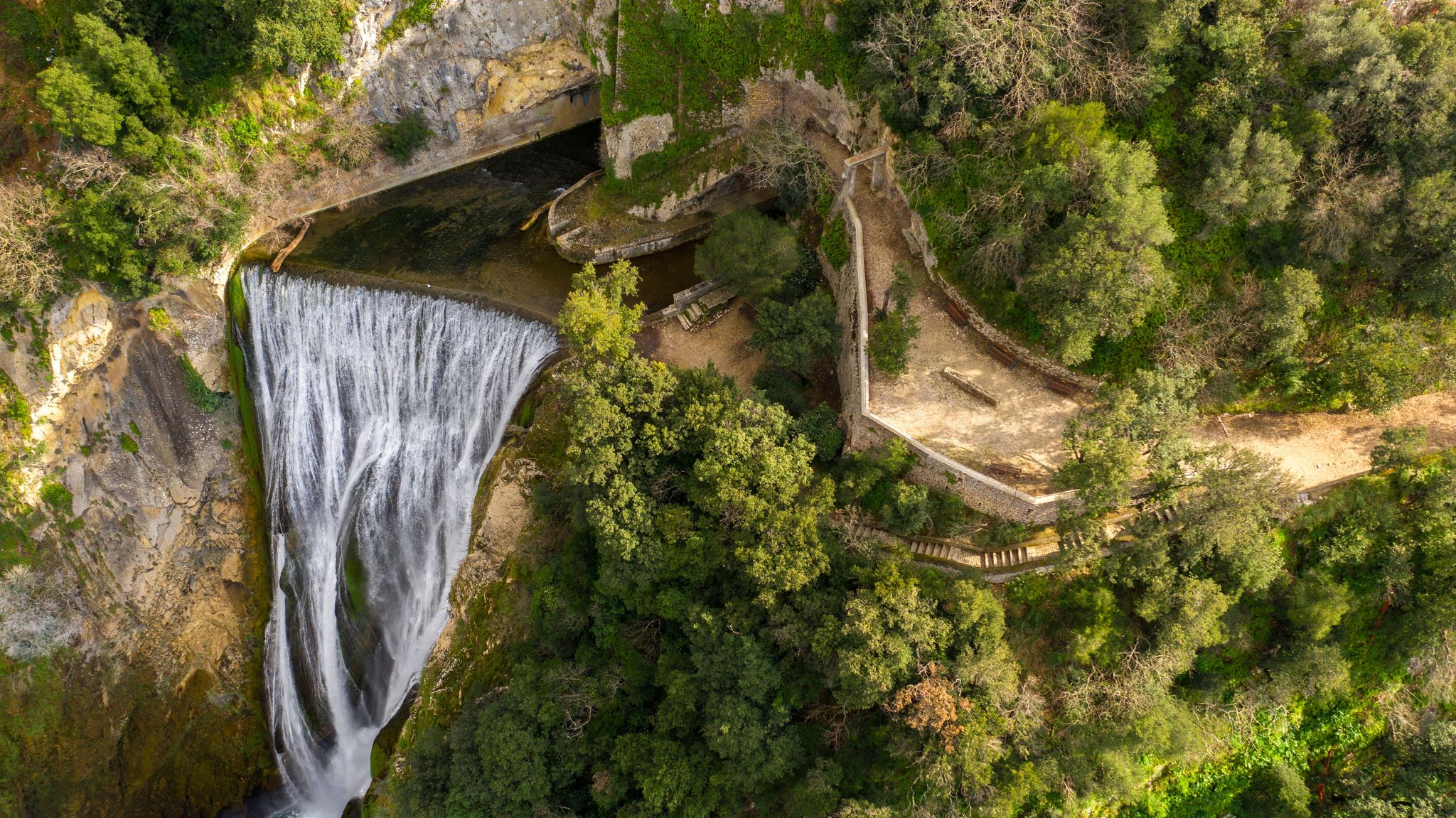 Aerial view of the Great Waterfall of Tivoli, near Rome, Italy. It is located in the park of Villa Gregoriana. Waterfall surrounded with natural cliffs and green trees.