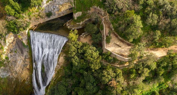 Aerial view of the Great Waterfall of Tivoli, near Rome, Italy. It is located in the park of Villa Gregoriana. Waterfall surrounded with natural cliffs and green trees.