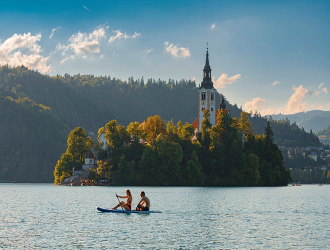Couple paddleboarding on Lake Bled with Bled Island and the Church of the Assumption in the background..jpg