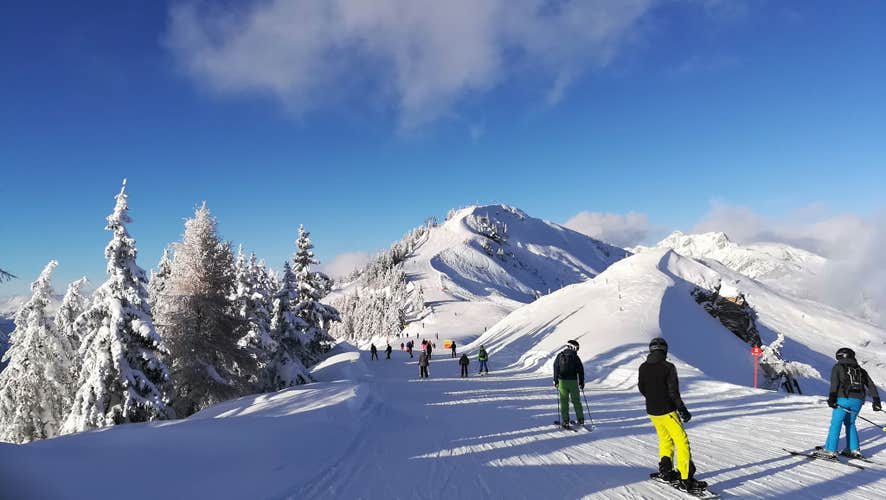 Alpine snowy landscape and ski slopes. Skiers and snowboarders in the Dorfgastein ski area. Skiing in the austrian alps. Amazing panorama of rocky mountains in winter. Snowy mountain peaks.