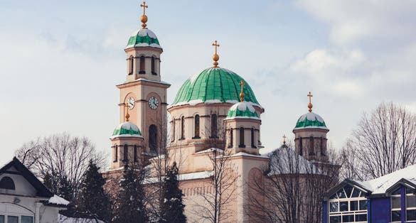 photo of view of Tuzla, Bosnia and Herzegovina. Main square in city centre. Minaret and mosque. Flag of Bosnia and Herzegovina.