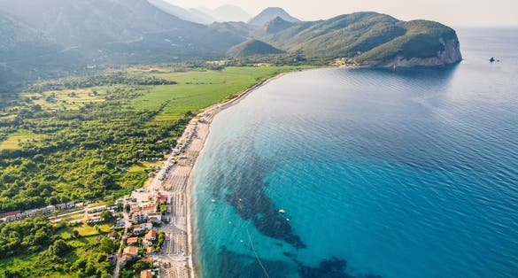 Photo of sea and sky with boats, rocks, a bright sunny day, clear water blue sea at Petrovac Buljarica beach, Montenegro.