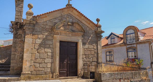 Small catholic Church or Capela de São Silvestre, Covilha, Portugal. Beautiful facade of a stone masonry mannerist chapel with wooden door, cross and bell tower.