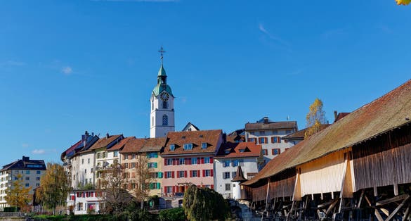 Photo of scenic view of medieval old town of Swiss City of Olten, Canton Solothurn, with covered wooden bridge and Aare River on a sunny autumn afternoon, Switzerland.