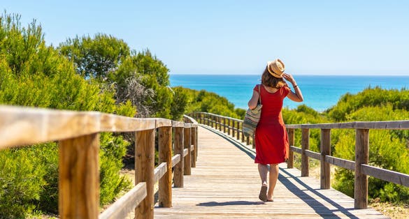 Photo of tourist on the wooden path to Playa Moncayo in Guardamar del Segura next to Torrevieja, Alicante. Community of Valencia.