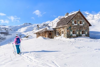 photo of young woman skier walking past mountain hut in Obertauern winter resort, Austria.