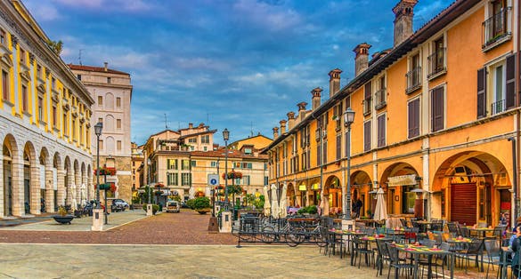 photo of view of Typical italian buildings and tables of street restaurants on Piazza del Mercato, Brescia, Italy.