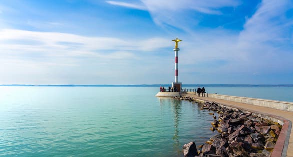photo of view of pier in Siofok Hungary with a gold angel statue and walking path