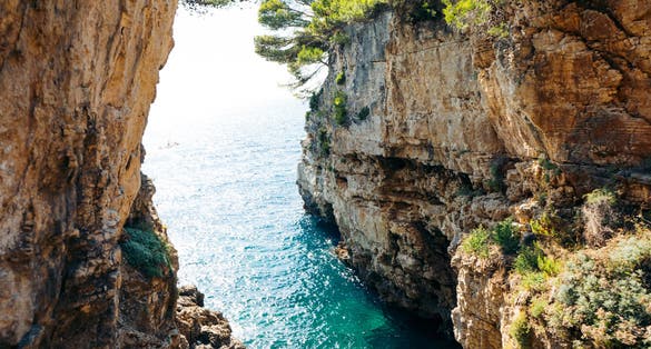 Photo of Sea canyon with high sheer cliffs descending to turquoise water, place for jump in Verudela Canyon at Verudela Peninsula, south from Pula, Croatia.