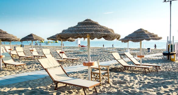Photo of Umbrellas and chaise lounges on the beautiful beach of Rimini in Italy.