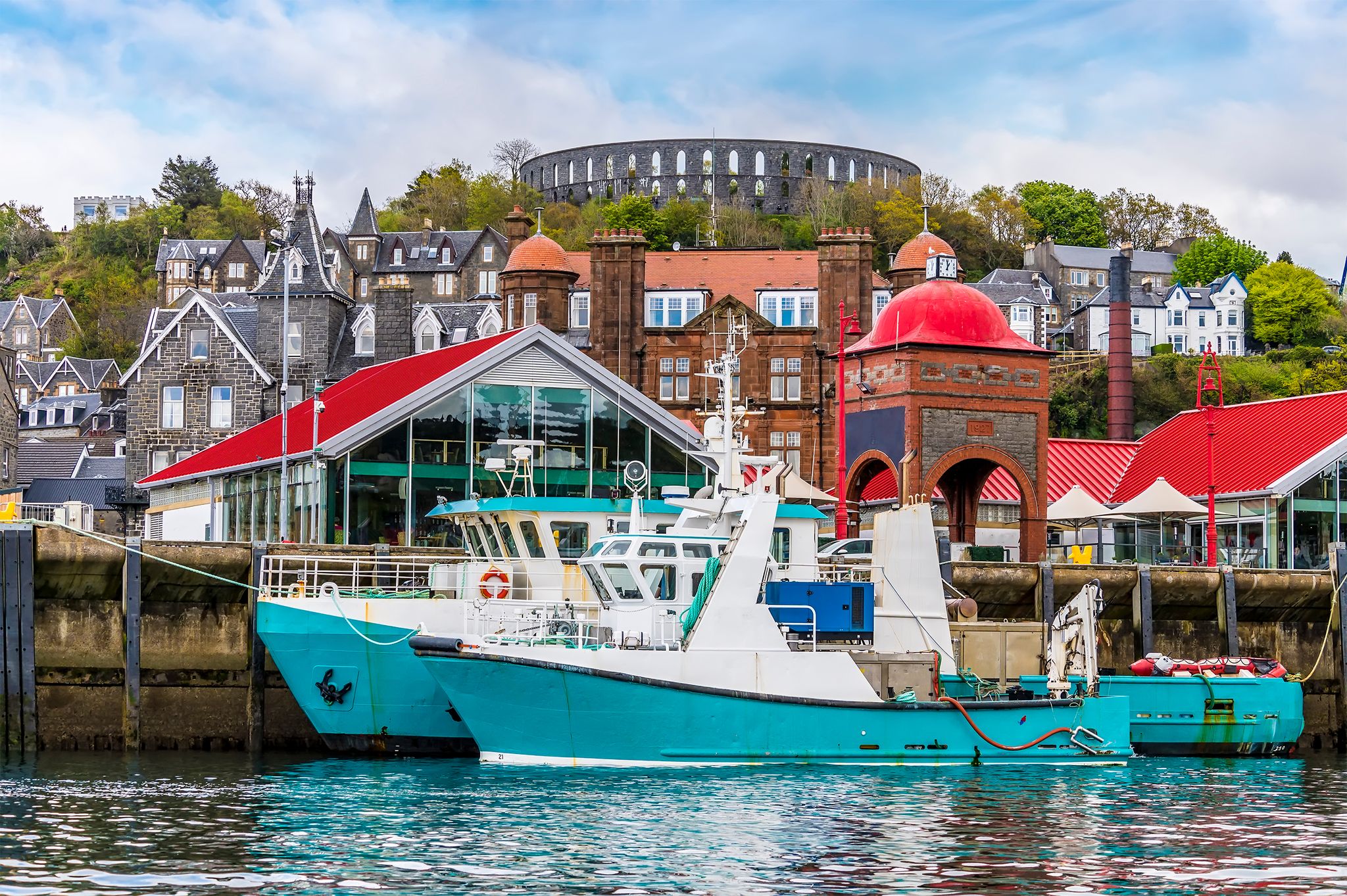 photo of view of A view of boats moored by the landing stage in the town of Oban, Scotland from Oban Bay on a summers day.