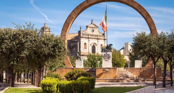 View of the village of Manduria, Lecce, Italy with the monument to the fallen and the Church of St. Francis (San Francesco). Transl.:"To our fallens civil Manduria for freedom in peace 1966"