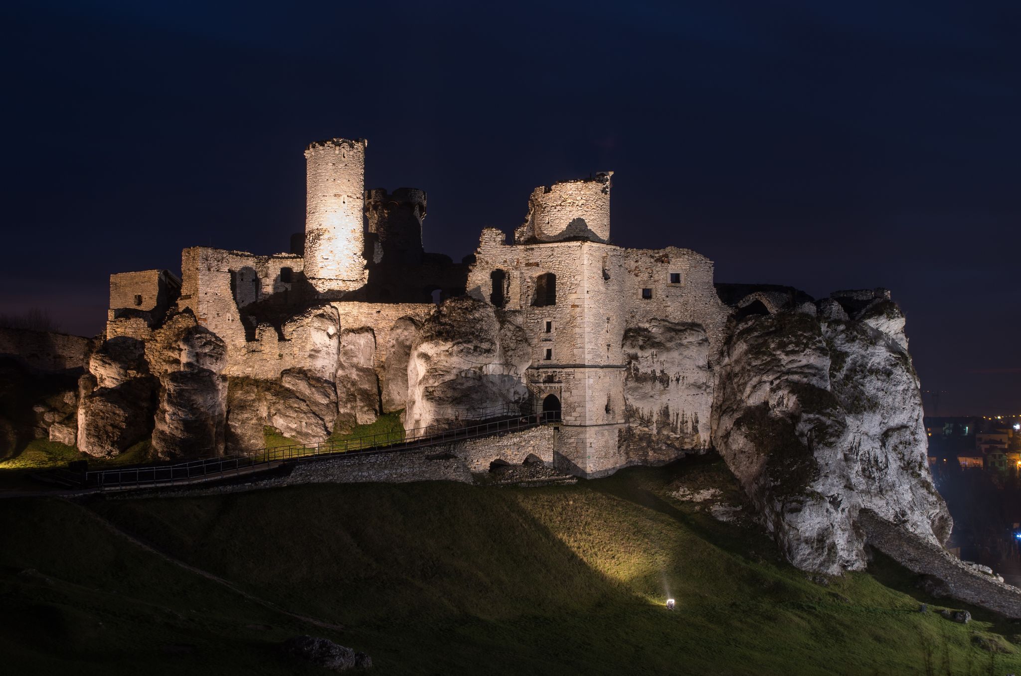 Photo of ruins of Ogrodzieniec Castle illuminated in the night in the south-central region of Poland.