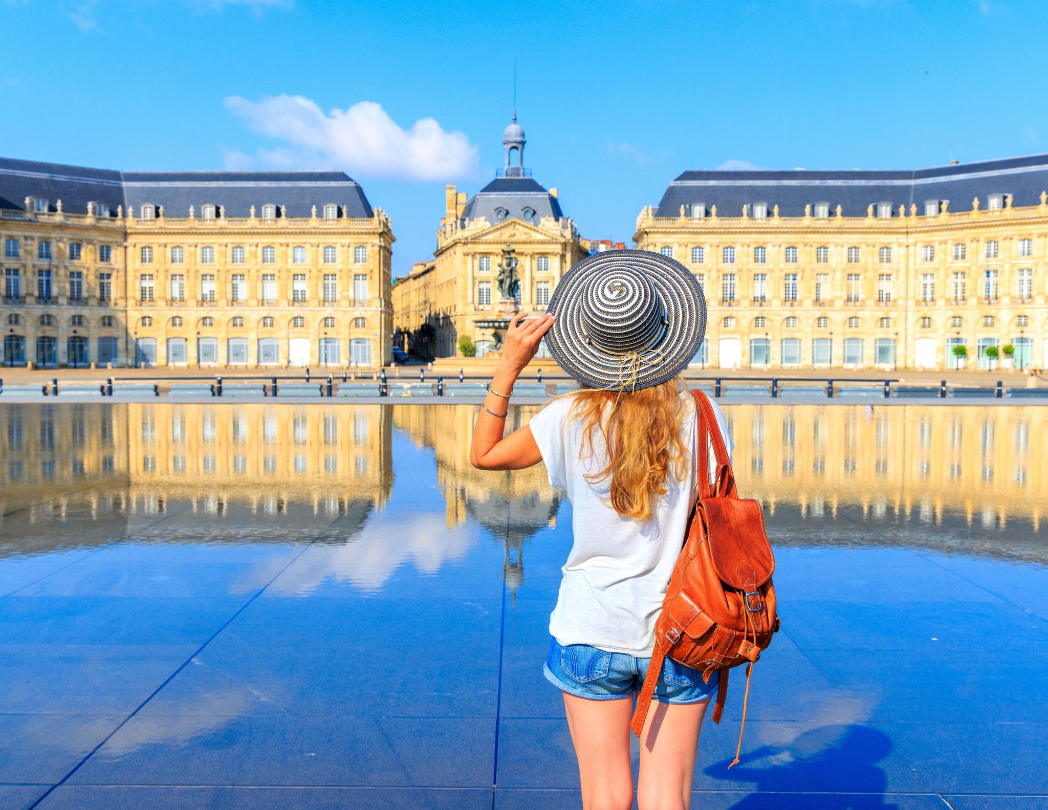 photo of woman with hat and bag on Miroir d'eau at the Bourse square, Bordeaux, France.