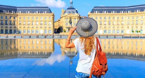 photo of woman with hat and bag on Miroir d'eau at the Bourse square, Bordeaux, France.
