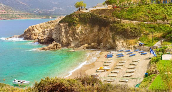 Photo of Sandy Evita and Karavostasi beach in sea bay of resort village Bali, aerial views of shore, washed by waves and sun loungers with parasols where sunbathing tourists, Bali, Rethymno, Crete, Greece.