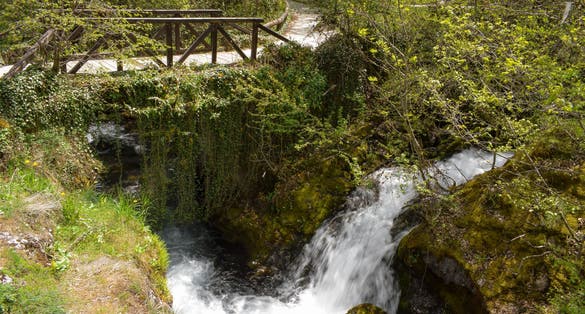 Photo of Cascade falls over mossy rocks under the wooden bridge, Vevcani springs, Jablanica mountain, Macedonia.