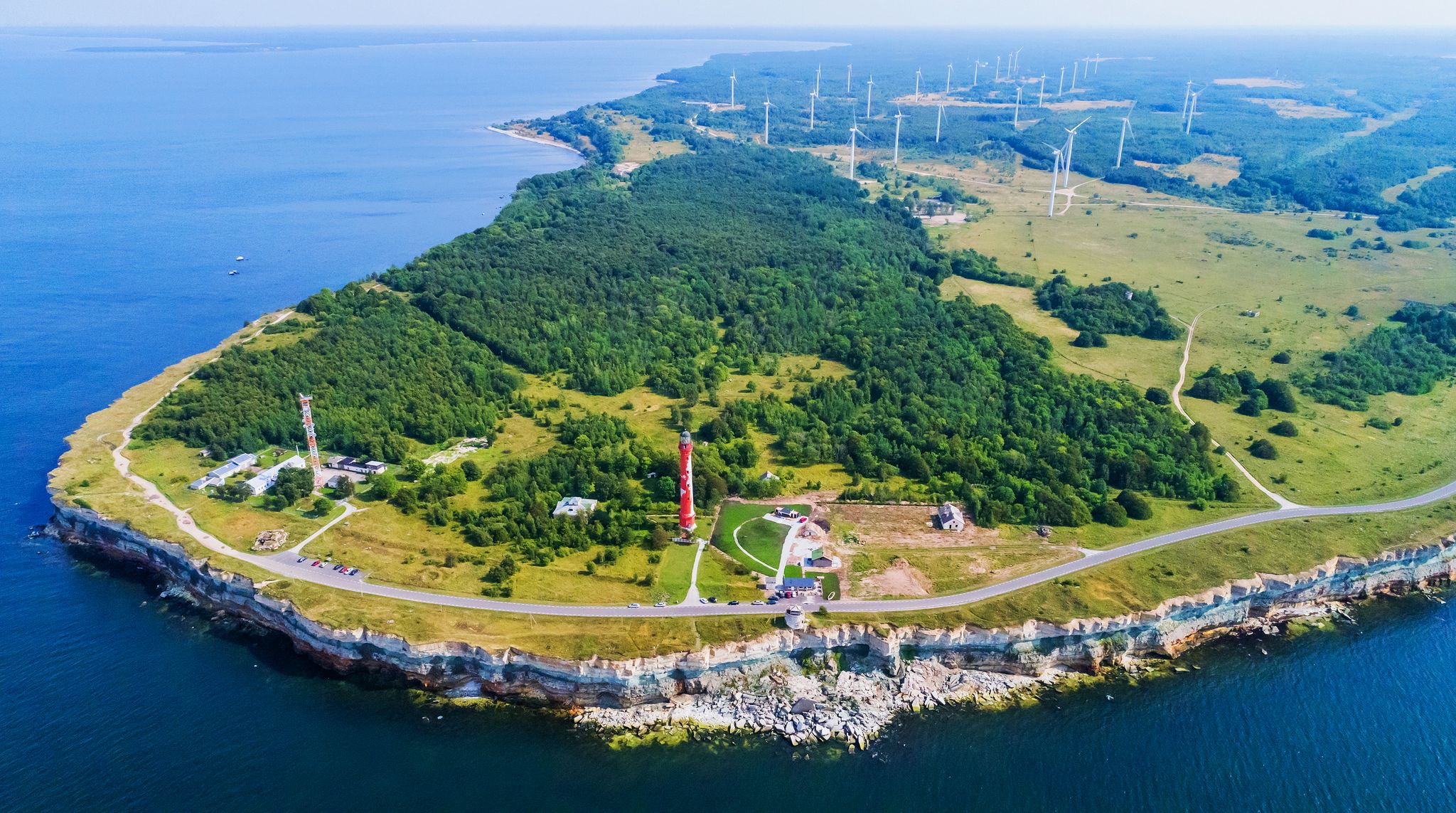 Photo of aerial view of limestone cliff on Pakri peninsula, Estonia with the historic lighthouses and wind farm on the background.