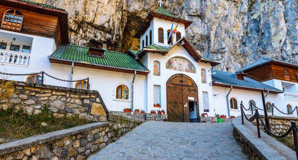 Photo of Ialomiței Cave with Saints Peter and Paul Church at the entrance. An orthodox Monastery built in a cave in Bucegi Mountains, Carpathians, Romania.