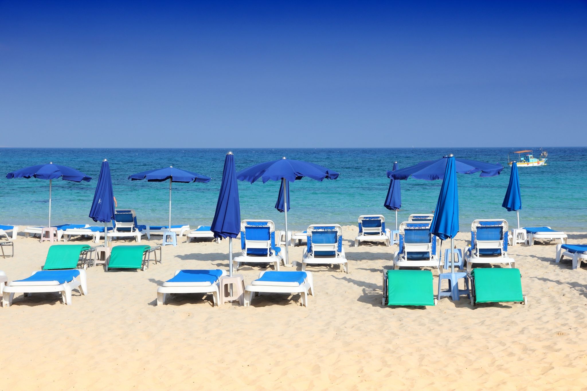 Photo of sandy Makronissos Beach with sunbeds and umbrellas, Cyprus.