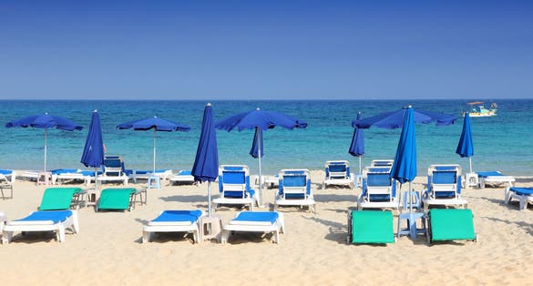 Photo of sandy Makronissos Beach with sunbeds and umbrellas, Cyprus.