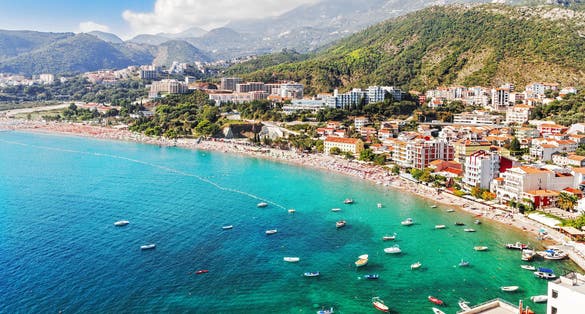 Photo of Becici town and beach in Montenegro , Sun umbrellas and loungers at the sandy beach. 