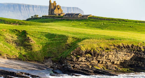 photo of view of Famous Classiebawn Castle in picturesque landscape of Mullaghmore Head. Spectacular sunset view with huge waves rolling ashore. Signature point of Wild Atlantic Way, Co. Sligo, Ireland