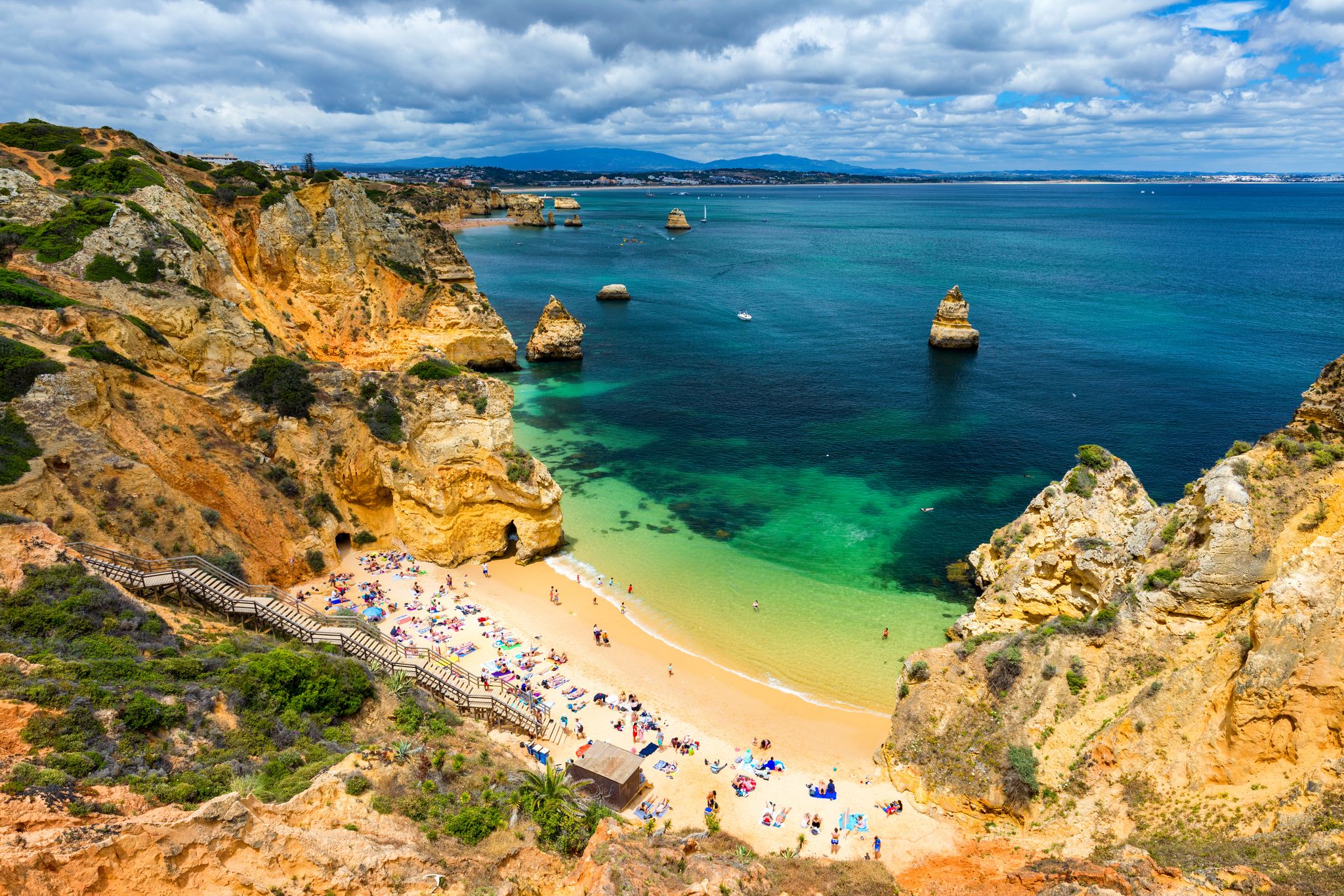 Photo of Camilo beach (Praia do Camilo) in Lagos, Algarve, Portugal. Wooden footbridge to the beach Praia do Camilo, Portugal. Picturesque view of Praia do Camilo beach in Lagos, Algarve region, Portugal.