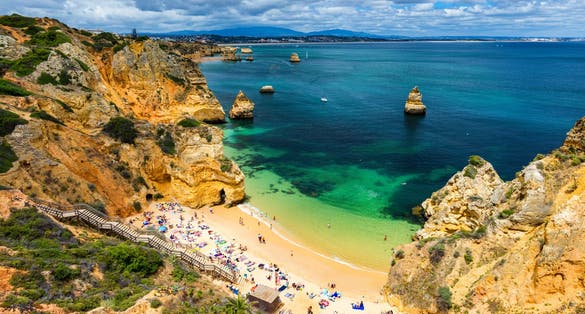 Photo of Camilo beach (Praia do Camilo) in Lagos, Algarve, Portugal. Wooden footbridge to the beach Praia do Camilo, Portugal. Picturesque view of Praia do Camilo beach in Lagos, Algarve region, Portugal.