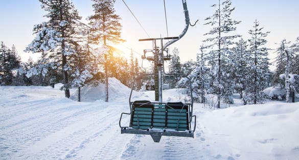 Photo of ski lift at sunrise in the beautiful snowy nature at mountain Ounasvaara, Rovaniemi. 