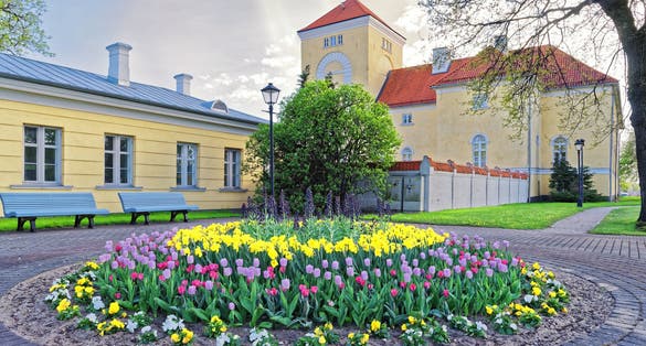 Photo of Ventspils Castle and tulips in the flowerbed in the Old toen in Latvia. The Castle was built by the Livonian Order. It is the oldest castle built by the Livonian Order.