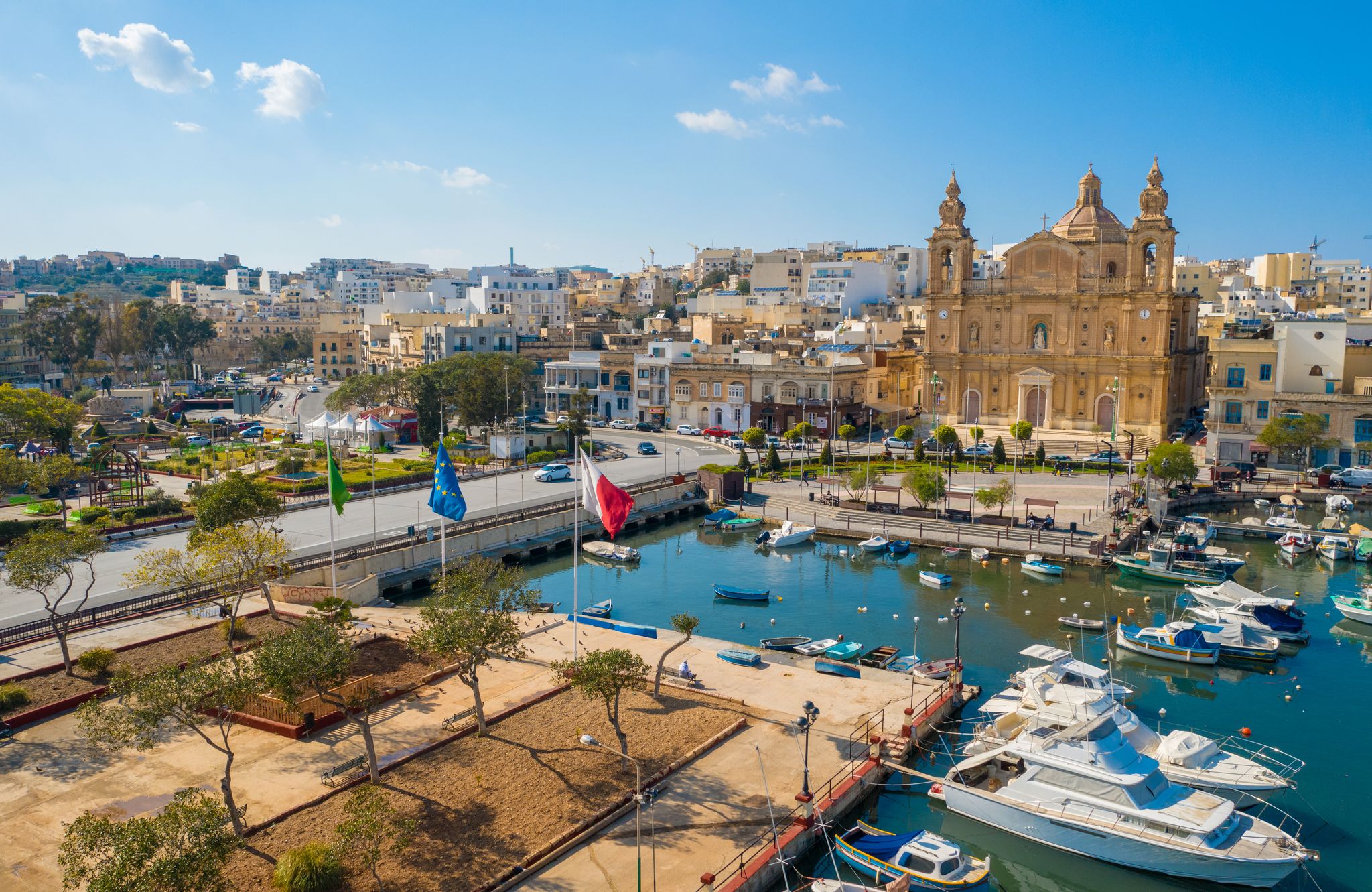 Photo of Aerial view of Msida marina bay and church. Sunny day, Maltese and Europe flags. Malta island.