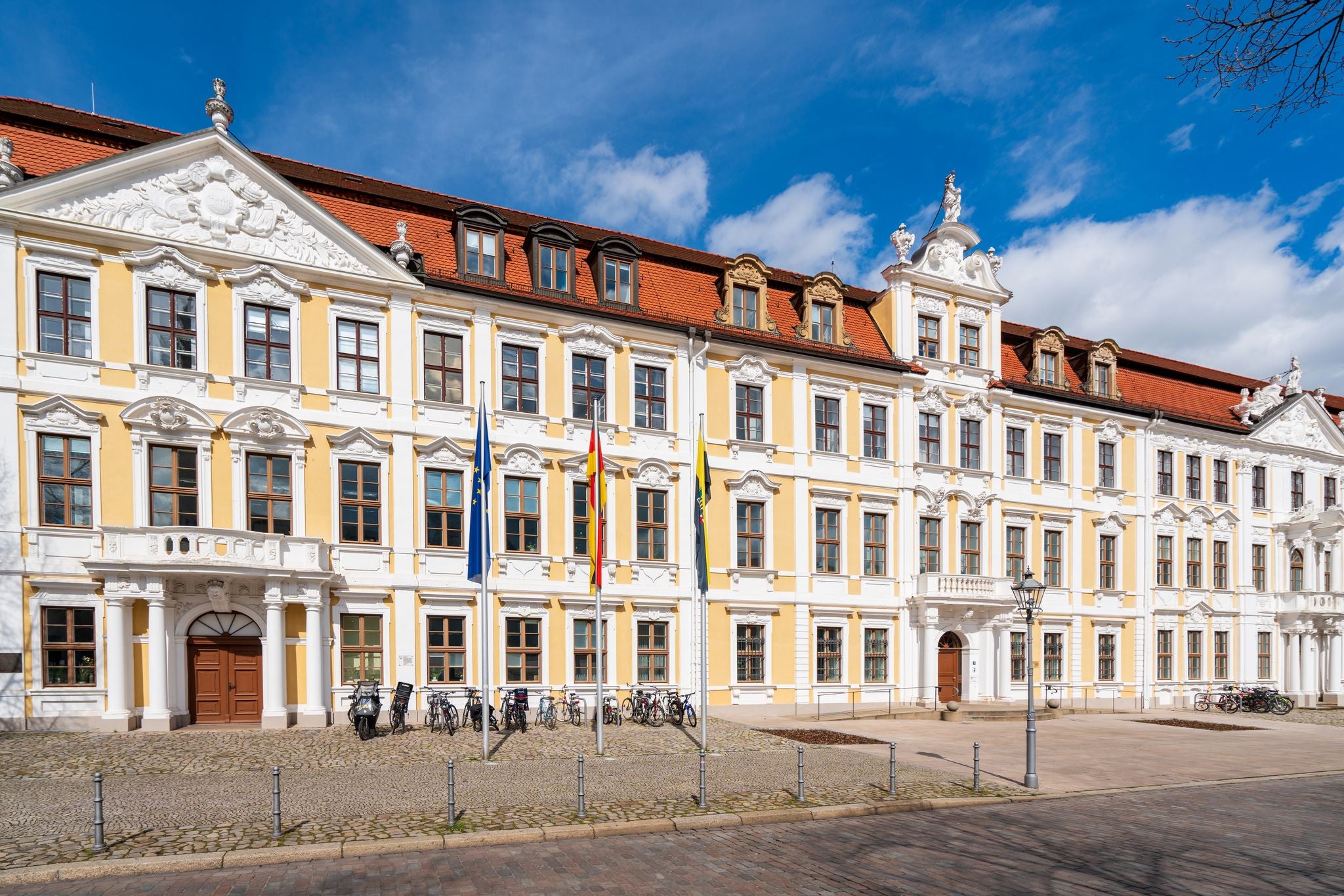 Building of the Saxon state parliament on the cathedral square in Magdeburg in sunshine with waving flags in front of it, Magdeburg Saxony-Anhalt, Germany 04-13-2023