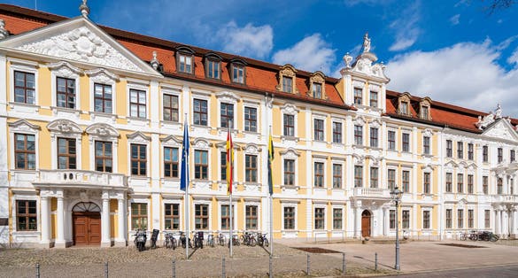 Building of the Saxon state parliament on the cathedral square in Magdeburg in sunshine with waving flags in front of it, Magdeburg Saxony-Anhalt, Germany 04-13-2023