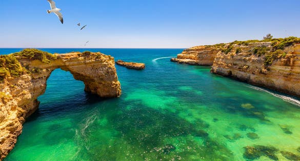 Photo of Natural arch above ocean, Arco de Albandeira, Algarve, Portugal. Stone arch at Praia de Albandeira, Lagoa, Algarve, Portugal. View of the natural arch Arco da Albandeira in the Algarve, Portugal.