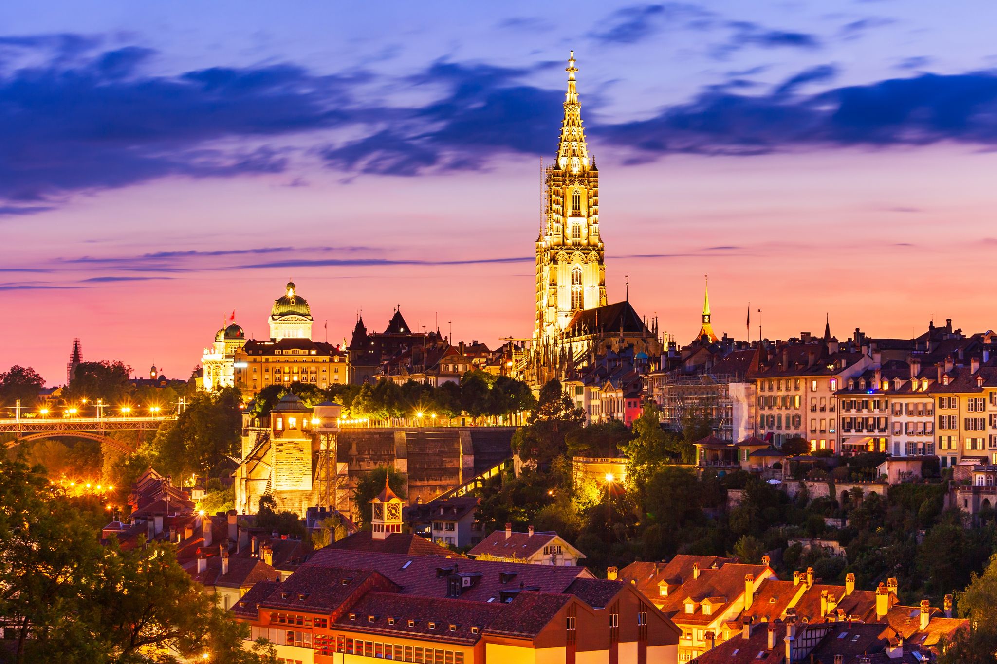 photo of night aerial view of Bern city with tower of Bern Minster in Switzerland.
