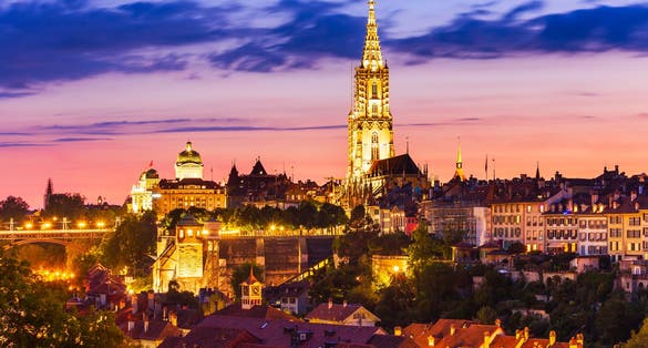 photo of night aerial view of Bern city with tower of Bern Minster in Switzerland.