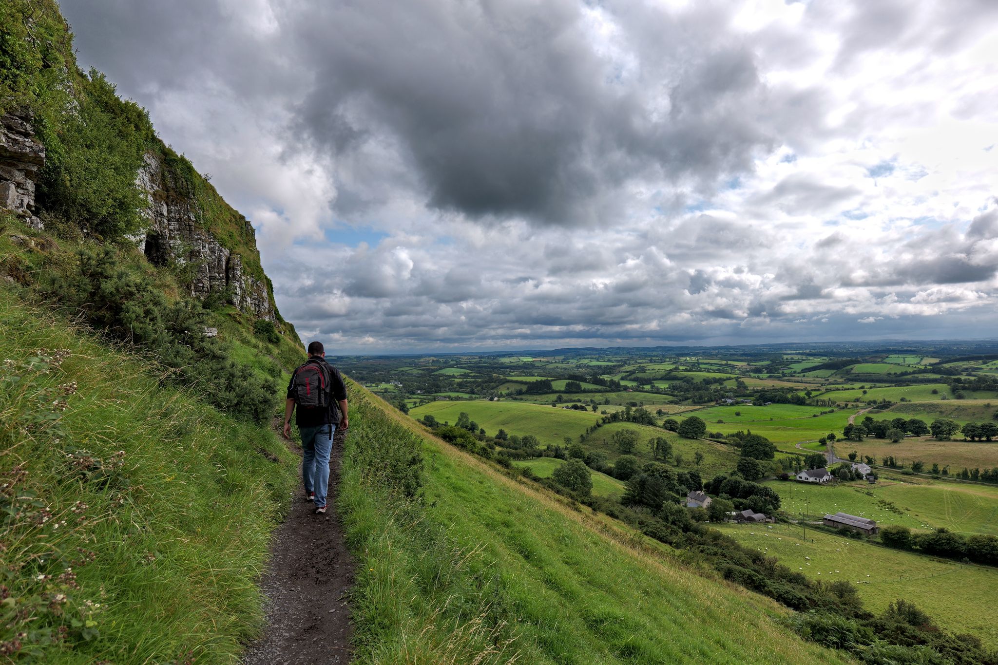 photo of Man walking towards the Caves of Kersh, overlooking the green rural landscape of County Sligo, Ireland